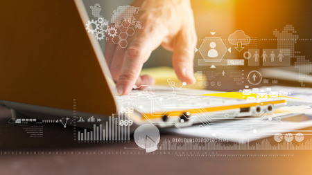Die Hand eines Mannes tippt auf die Tastatur eines Laptops. Das Bild wird von Diagrammen und Symbolen für Daten überlagert.
